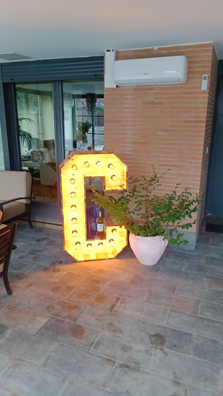 Letra C marquee iluminada con bombillas instalada en terraza de boda por TOVARNA